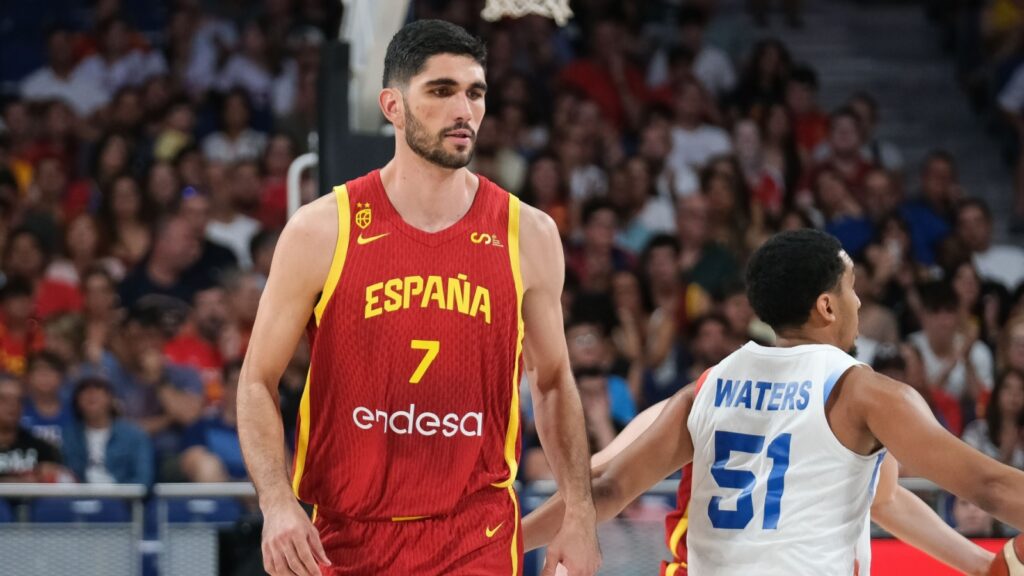 Basketball player in red Spain jersey number 7 on the court with a crowded arena backdrop.