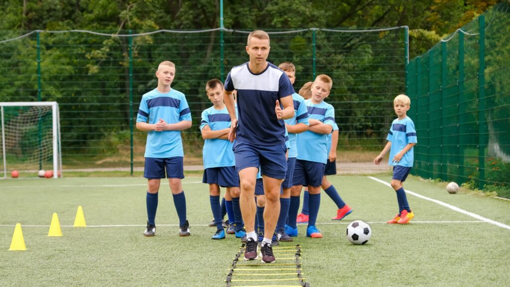 Young coach showing the players exercises to improve their game skills. 