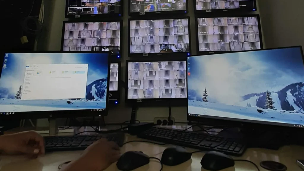 a person monitors numerous screens displaying live cctv security camera