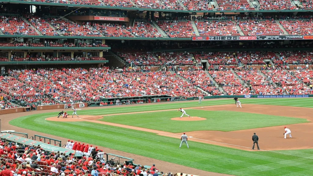 Fans watch a baseball game from the stands at a packed stadium.