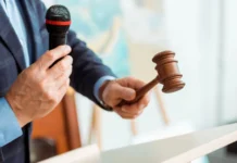 cropped view of auctioneer in suit talking with microphone and