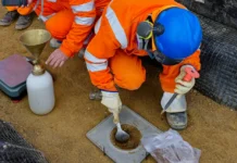 Workers performing a sand cone density test to measure soil compaction