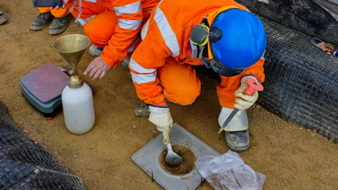 Workers performing a sand cone density test to measure soil compaction