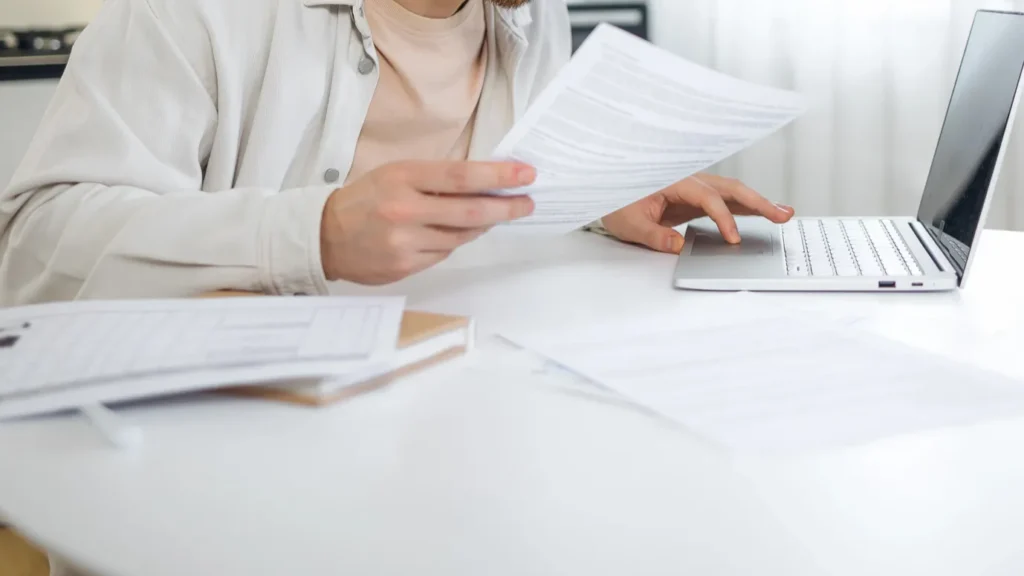 man reviewing important documents and looking at papers and laptop