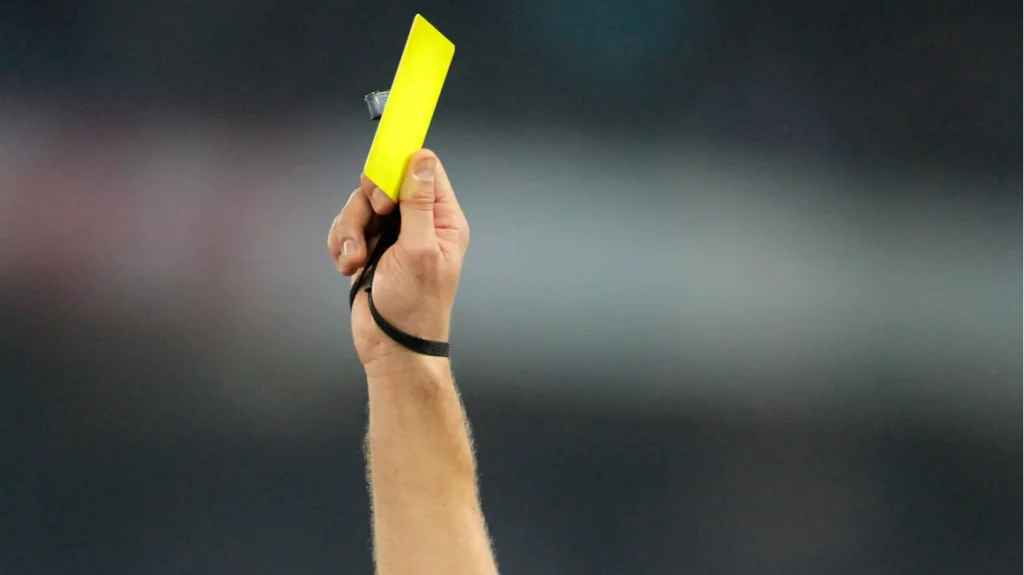A soccer referee holding a yellow card