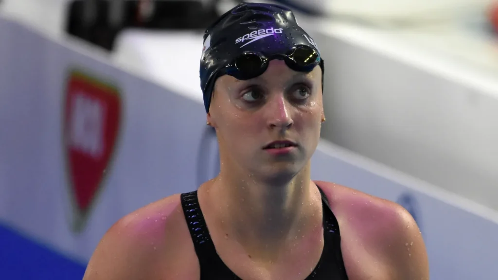 Katie Ledecky wearing a swimming cap and goggles during a competitive swimming event.