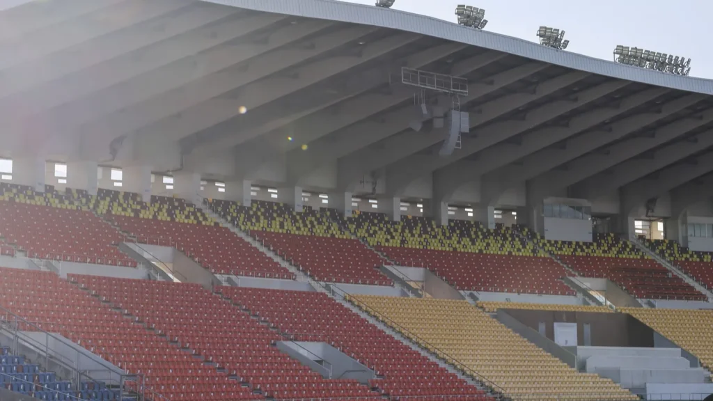 quiet empty stadium stand with red and yellow seat rows