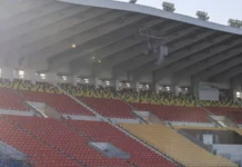 quiet empty stadium stand with red and yellow seat rows