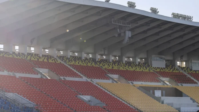 quiet empty stadium stand with red and yellow seat rows