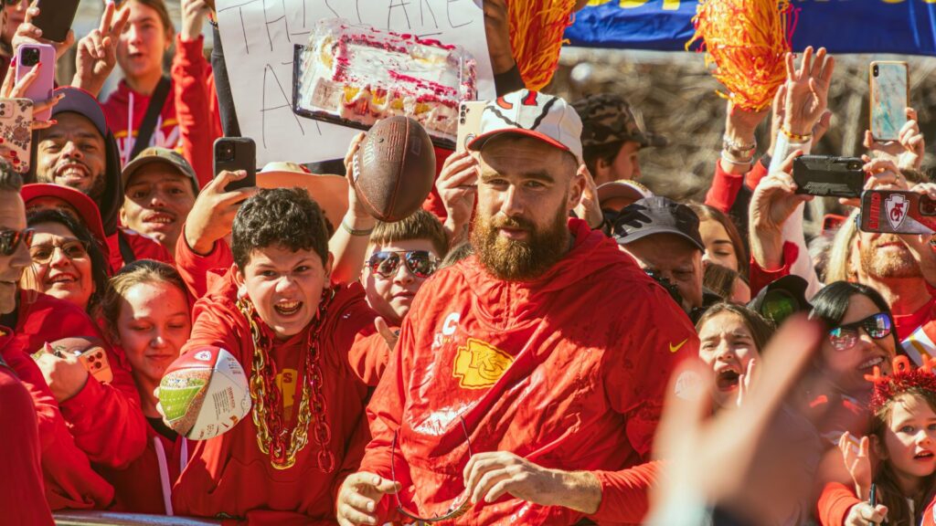 Travis Kelce, who plays the tight end position for the Kansas City Chiefs NFL football team interacts with many fans during the Super Bowl LVIII Parade