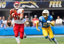 Travis Kelce #87 catches a pass next to LA Chargers safety AJ Finley #24 during an NFL football game at SoFi Stadium.