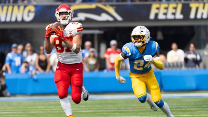 Travis Kelce #87 catches a pass next to LA Chargers safety AJ Finley #24 during an NFL football game at SoFi Stadium.