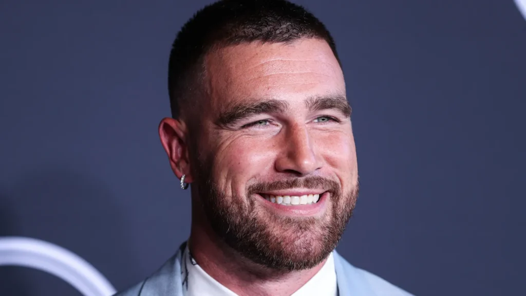 Travis Kelce smiling for the camera at an event.