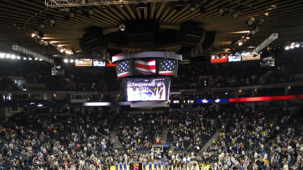 basketball players and oakland fans stand with hats removed duri