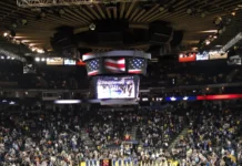 basketball players and oakland fans stand with hats removed duri