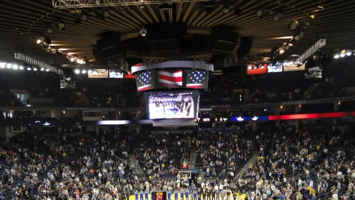 basketball players and oakland fans stand with hats removed duri