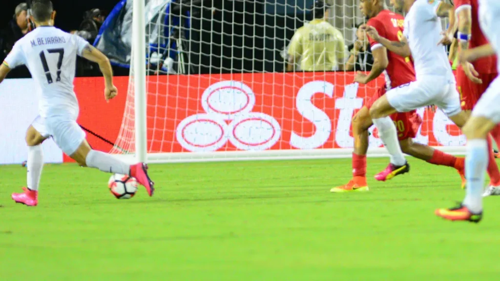 Players running on the field to make a goal.