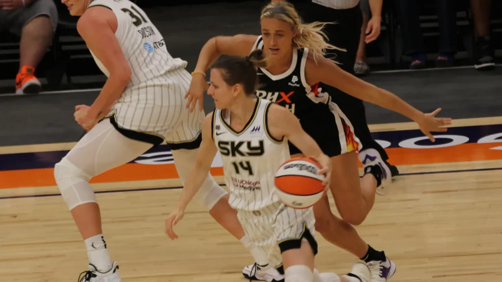 Sophie Cunningham chasing opponent player on the basketball court.