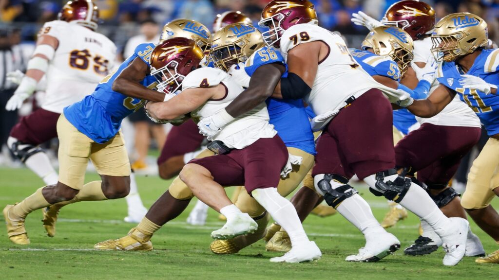 Arizona State running back Cam Skattebo #4 runs against UCLA defensive line Gary Smith III #58 and defensive back Alex Johnson #36 during an NCAA college football game