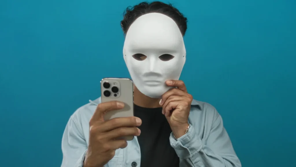 A young man wearing a mask and holding a smartphone
