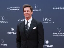 Tom Brady at an event againt a navy blue background.