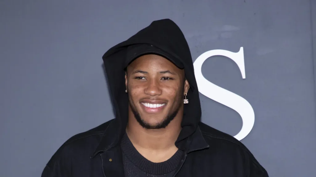 Saquon Barkley smiling and posing for the photography with grey background.
