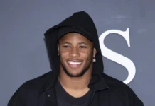 Saquon Barkley smiling and posing for the photography with grey background.