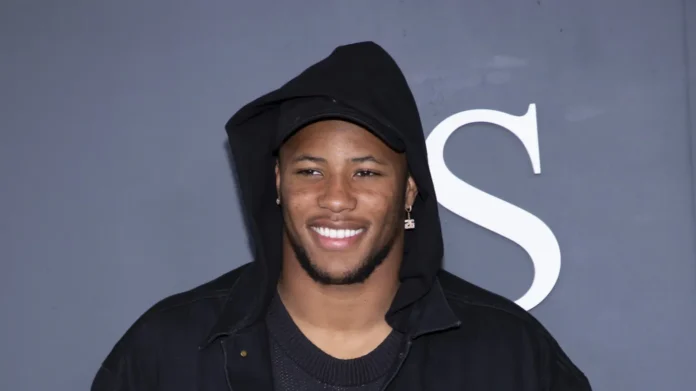 Saquon Barkley smiling and posing for the photography with grey background.