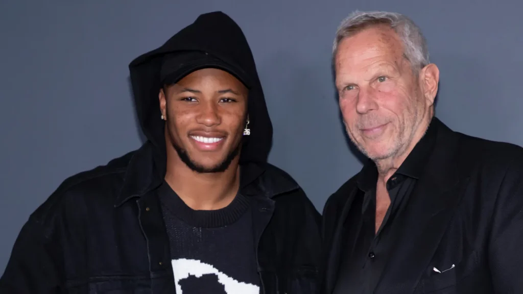 Saquon Barkley with Steve Tisch posing for camera against grey background.