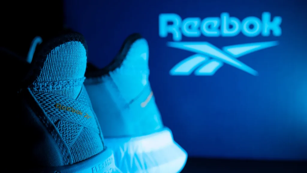 Reebok athletic shoes displayed in blue lighting with the Reebok logo in the background