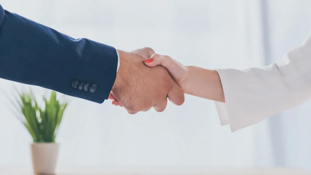 partial view of businessman shaking hands with woman while sitting
