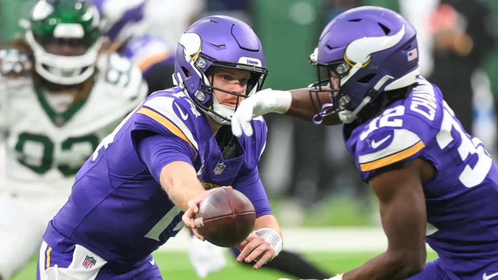 Sam Darnold of the minnesota vikings giving the ball to other player.