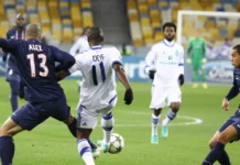 Paris Saint-Germain defenders challenge a white-jerseyed opponent for possession of the ball during a football match.