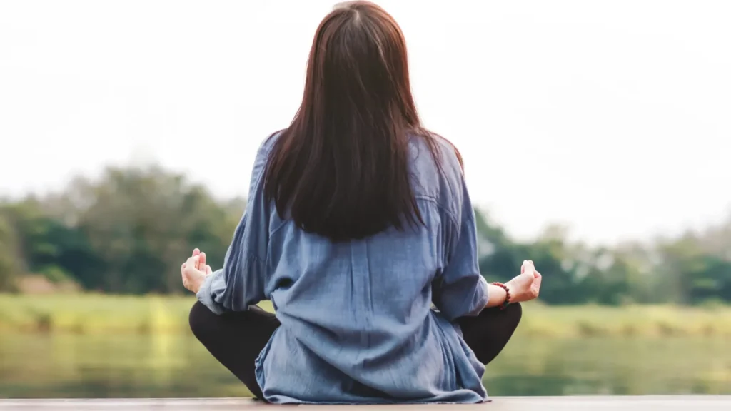 Young woman practices outdoor yoga in lotus position.